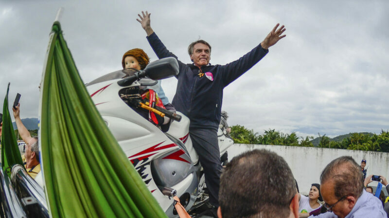 El presidente brasileño, Jair Bolsonaro, posa en una motocicleta mientras saluda a simpatizantes en un encuentro con alcaldes de su partido político. Foto: EFE.