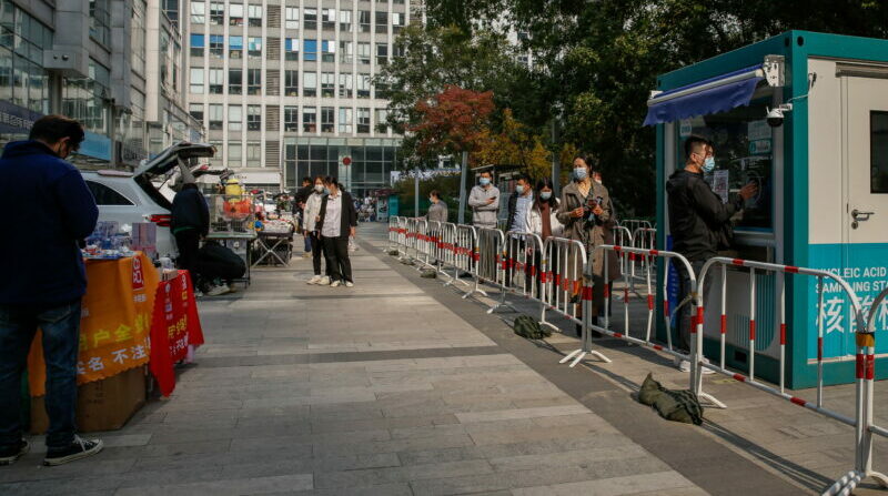 Personas en fila de un puesto de pruebas PCR, en un estacionamiento en China. Foto: EFE.