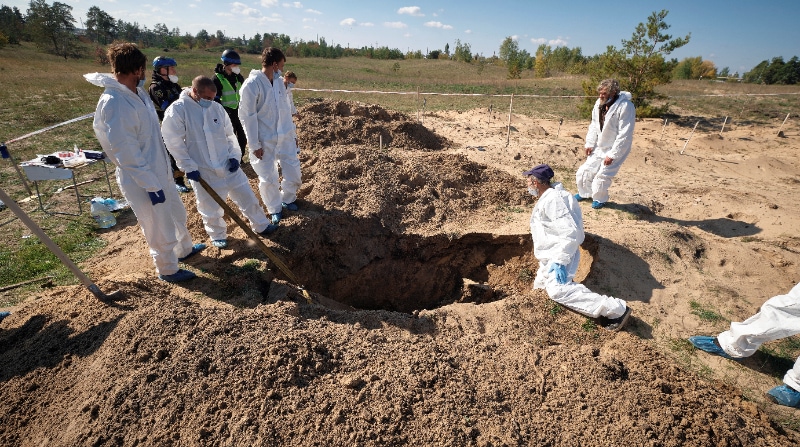 Técnicos forenses trabajan en un lugar de entierro cerca de Limán, área de Donetsk, en Ucrania. Las autoridades ucranianas han comenzado a exhumar e identificar los cuerpos de las tumbas parcialmente sin marcar. Foto: EFE