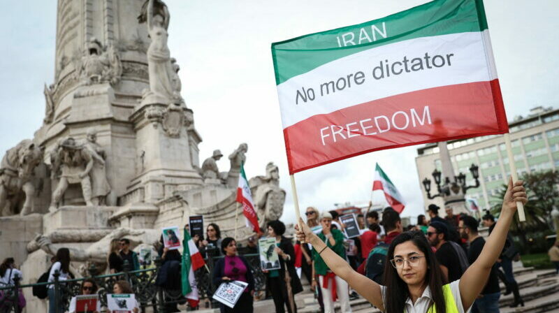 Joven despliega una pancarta en contra del régimen totalitario de Irán, en Lisboa. Foto: EFE.