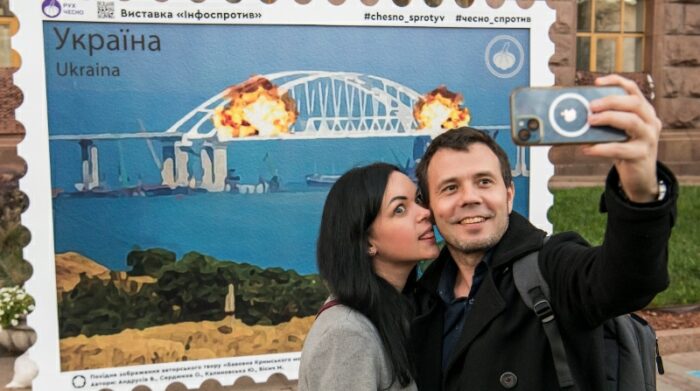 Los ucranianos se toman selfies y posan para fotos frente a la impresión de un colectivo de artistas de las explosiones en el puente del estrecho de Kerch en un sello llamado "Algodón sobre el puente de Crimea" en el centro de Kyiv, Ucrania, el 8 de octubre de 2022. Foto: EFE