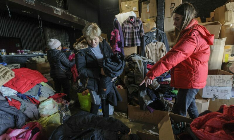 Una voluntaria ausculta prendas de vestir en una bodega que contiene donaciones enviadas a Ucrania para socorrer a la población durante el invierno. Foto: EFE.