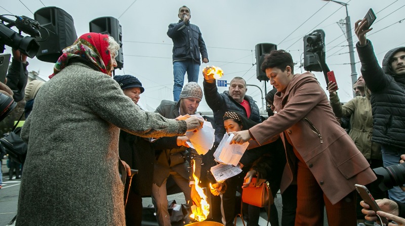 Ciudadanos moldavos queman sus recibos de gas y energía durante un acto de protesta efectuado en contra de las políticas del gobierno en Chisinau. Foto: EFE.