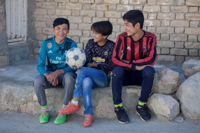 Ali Sina, de 13 años, se sienta con su hermano y su amigo en la calle cerca de su casa donde juega al fútbol en Hazara Town, Quetta, Pakistán. Luego de seis meses de haber sido picado por una mosca de la arena, que le provocó Leishmaniasis, Ali comenzó su tratamiento en el Centro Médico Bolan en Quetta, apoyado por MSF. Octubre de 2018. Foto: Khaula Jamil 