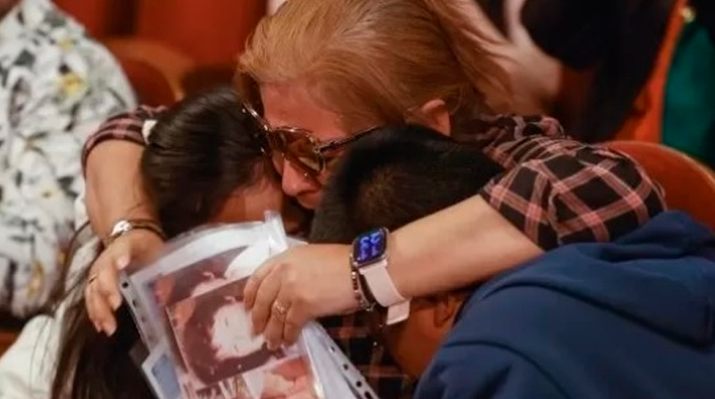 Perla, la migrante peruana ganadora de parte del Gordo de Navidad, se abraza con sus hijos. Foto: EFE