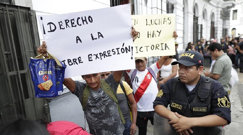 Dos hombres levantan carteles de protesta durante la intervención policial a la Confederación Campesina del Perú (CCP), este 17 de diciembre, en Lima (Perú). Foto: EFE