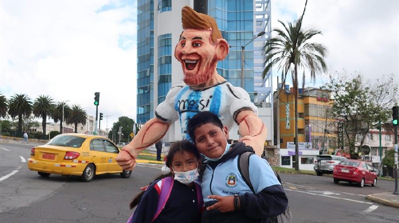 Dos niños posan junto a un monigote de Lionel Messi cerca de un puesto de venta de 'años viejos'. Foto: EFE