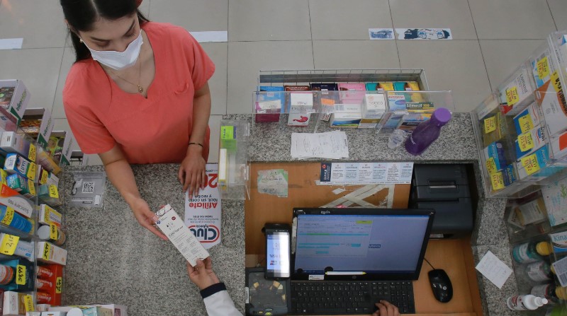Una ciudadana adquiere medicina para combatir síntomas gripales y una prueba rápida para detectar covid, en una farmacia de la capital. Foto: Julio Estrella / EL COMERCIO