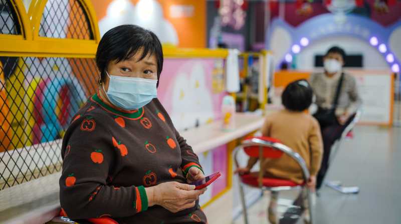 Una mujer protegida con una mascarilla utiliza su móvil en un centro comercial de Pekín el 11 de enero. Foto: EFE/WU HAO