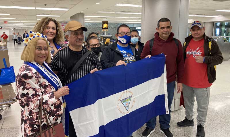 Un grupo de desterrados nicaragüenses sostienen la bandera de su país junto a activistas a su llegada al Aeropuerto Internacional de Miami, Florida. Foto: EFE
