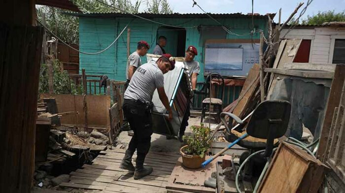 Policías ayudan a recuperar pertenencias en las viviendas de habitantes afectados por el desborde del río Chillón, en Perú. Foto: EFE