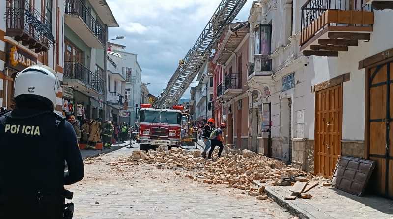 Personal del emergencia luego de retirar el cuerpo, continúa laborando en el sitio que cayó al fachada de una casa sobre un auto, en Cuenca. Foto: Claudia Pazán / EL COMERCIO