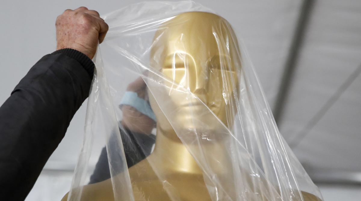 Un trabajador cubre con un plástico una estatuilla de los Premios Oscar. Foto: EFE