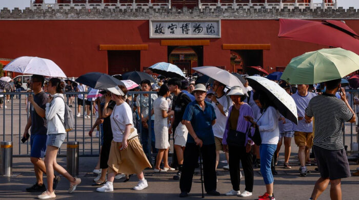 Personas caminan con ropa fresca y protección para el sol, en las afueras del Museo del Palacio en Pekín, en China. Foto: EFE