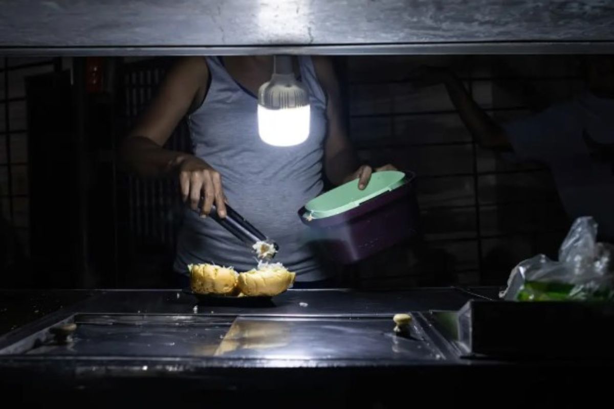 Una persona vende comida ayudada con un bombillo en medio de la oscuridad durante un corte eléctrico, el 29 de febrero de 2024 en Maracaibo, Venezuela.