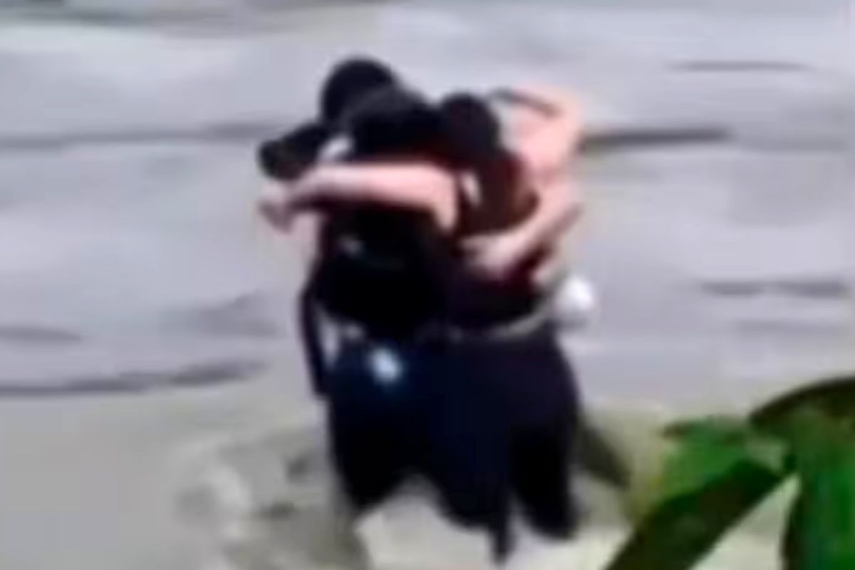 Tres jóvenes se abrazan antes de ser arrastrados por las inundaciones.